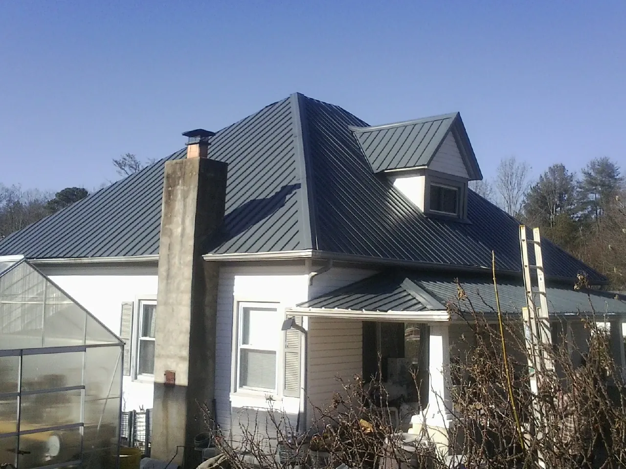 Dark blue standing seam metal roof on a white farmhouse with dormer — Slate & Tile Roof Repair by Roofing Brothers in Mill Run