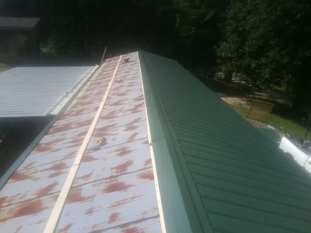 Old rusted panels beside newly installed green metal roofing — Wind Damage Roof Repair by Roofing Brothers in Mill Run