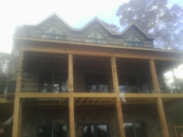 Dormers and porch framing on a large log home under construction — Roof Coating work by our crew in Mill Run