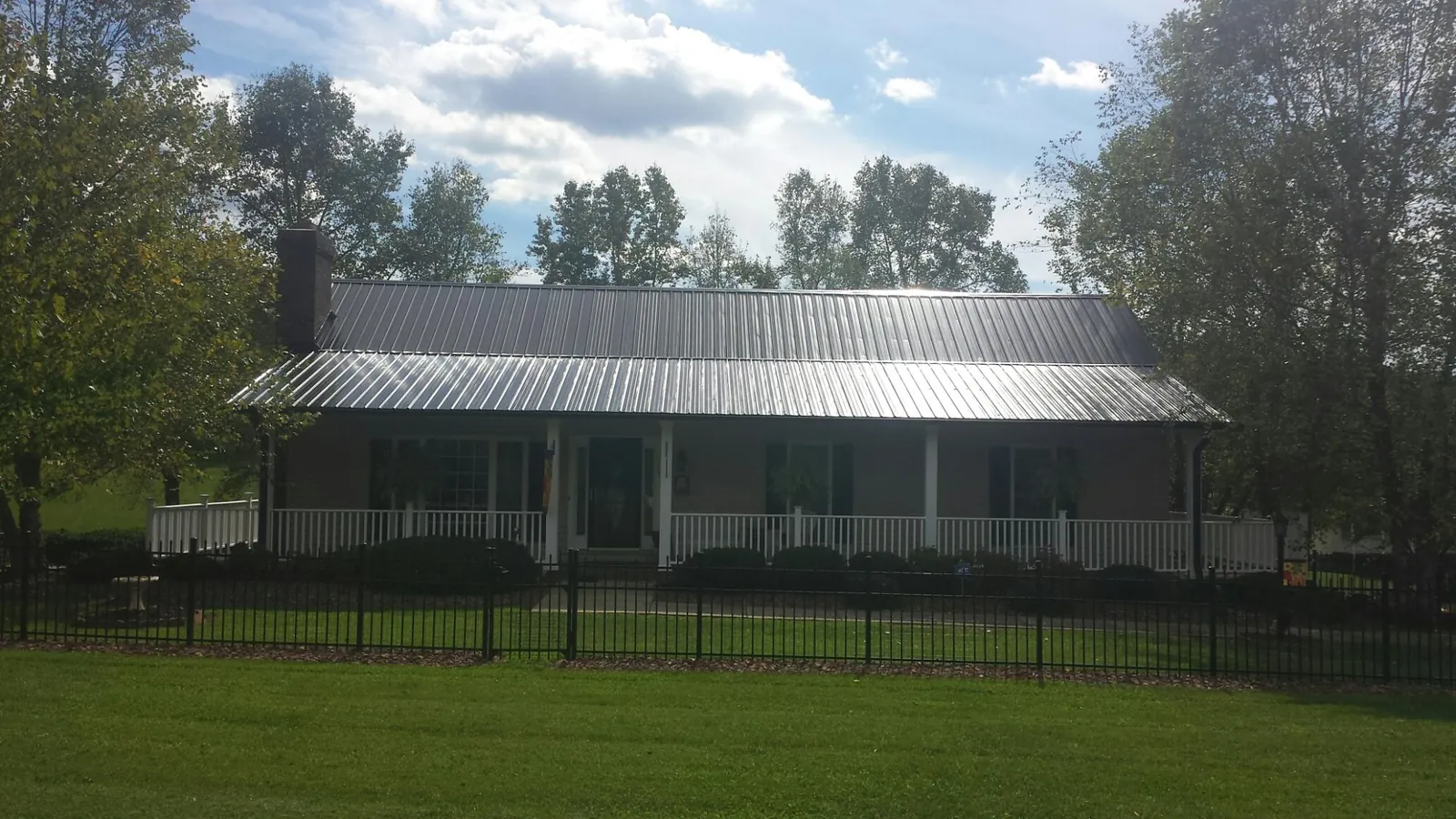 Gray metal roof on a brick ranch with a full width front porch — Gutter Guard Installation work by our crew in Mill Run