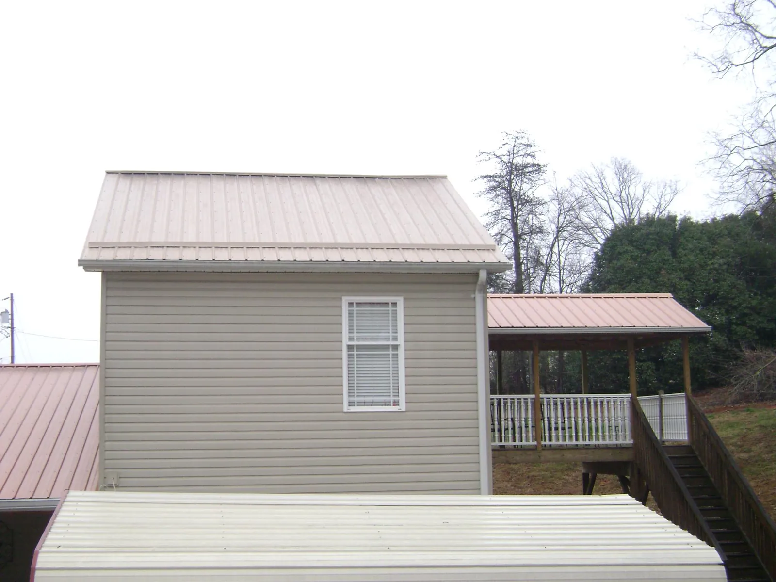 Tan metal roofs on a two story addition and attached porch, from a Roof Replacement job in Mill Run